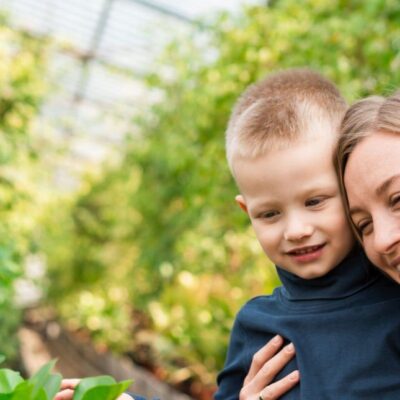 Mom hugs her son in a greenhouse with plants